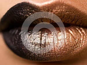 Lips make-up. Beauty high fashion trendy black with gold colour gradient lips makeup sample, mouth closeup.