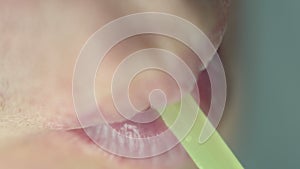 Lips of a man who drinks from a yellow plastic tube, top view, macro shooting