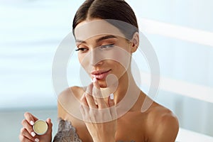 Lips Skin Care. Woman With Beauty Face Applying Lip Balm On