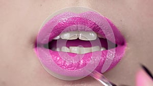 Lipstick are applied to the woman`s lips, making of the bright evening makeup, lips makeup, makeup artist`s work, close