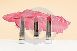 Lipstick different colors, shades options. Cosmetics on nude background. Beautiful examples of lipsticks, pink and red