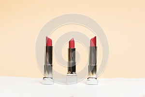 Lipstick different colors, shades options. Cosmetics on nude background. Beautiful examples of lipsticks, pink and red