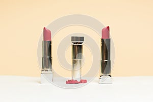 Lipstick different colors, shades options. Cosmetics on nude background. Beautiful examples of lipsticks, pink and red. One