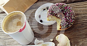 Lipstick mark on coffee cup and half eaten chocolate doughnut with sprinkles