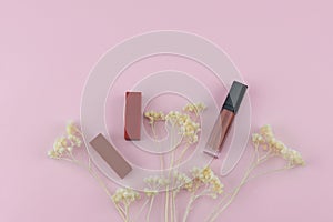 Lipsticks and lip gloss decorate with white dried flowers