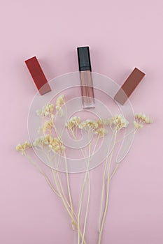 Lipsticks and lip gloss decorate with white dried flowers