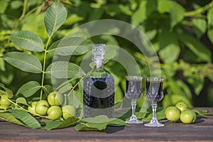 Liqueur from young green walnuts, remedy for stomach ache. Tincture of green walnuts in a glass bottle in the garden