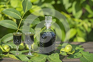 Liqueur from young green walnuts, remedy for stomach ache. Tincture of green walnuts in a glass bottle on a table in the garden