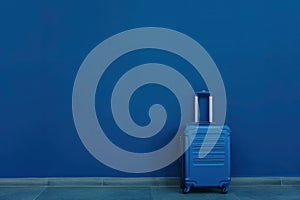 A liquid blue suitcase rests against an electric blue wall