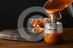 Liquid caramel pouring from pot into jar on table