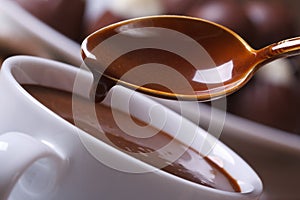 Liquid chocolate dripping from the spoon in a cup