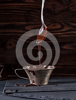 Liquid chocolate dripping from spoon into cup