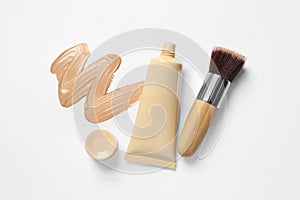 Liquid foundation, makeup brush and swatch on white background, flat lay