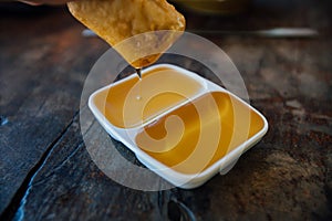 Liquid honey in a white sauceboat from two sections. On a wooden table