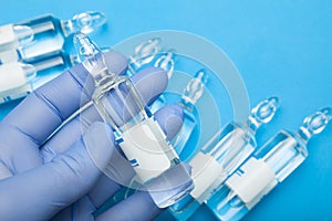 Liquid medications in ampoules in the doctor`s hand in the glove