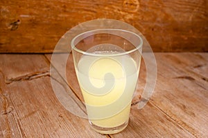 Liquid milk whey in a glass on rustic wooden background. Protein coctail. Dairy food manufacturing concept
