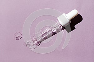 Liquid oil serum drop in pipette isolated on pastel violet background. Retinol, aha acid, collagen skincare fluid, photo