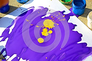 Liquid purple with yellow paint blot on white paper