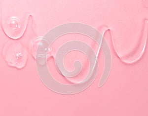 Liquid shower fluid gel flowing over pink background, texture, facial treatment, liquid soap