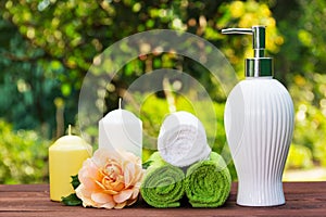 Liquid soap, a stack of towels, candles and a fragrant rose. Spa set for body care. Spa concept.