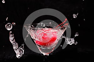 liquid splashing into a glass with cherries in a black background