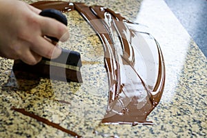 Liquid tempered chocolate applied in a thin layer on a granite table for it cooling