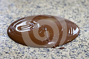 Liquid tempered chocolate poured on a granite table