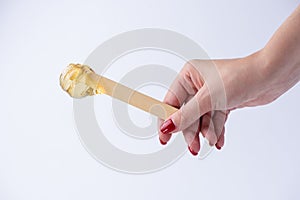 Liquid yellow sugar paste or wax for depilation on a stick close-up on a white background