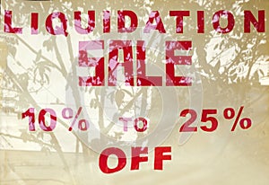 LIQUIDATION SALE sign in red with plant reflections in window.