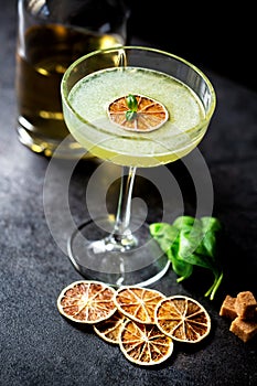 Liquor bottle, cocktail glass, brown sugar, basil leaves and dried lemon slices