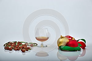 Liquor glass with Christmas ornaments and hazelnuts, white backgrounds and reflections