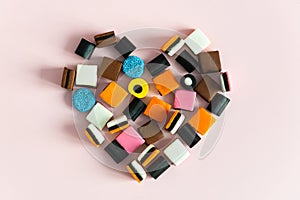 Liquorice Allsorts Sweets in heart shape on pink background. Copy space