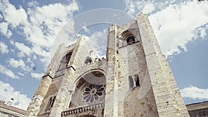 Lisbon Cathedral on a summer day. Action. Low angle view of beautiful ancient building on a blue cloudy sky background.