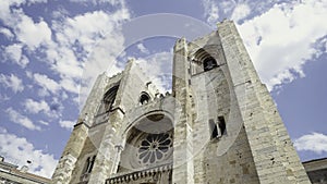 Lisbon Cathedral on a summer day. Action. Low angle view of beautiful ancient building on a blue cloudy sky background.