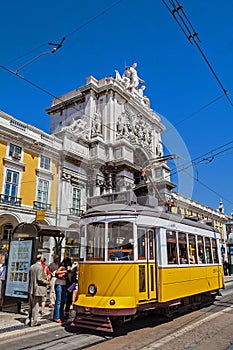 Lisbon, Portugal: Carris vintage yellow tram and Rua Augusta Street Triumphal Arch in Praca do Comercio aka Co