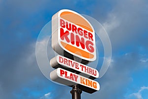 Burger King logo sign in the sky along a road, drive thru and play king, blue sky with clouds.