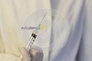 Medic ,scientist, pharmacist holding Syringe with AstraZeneca logo on lab coat. Coronavirus, Covid-19 vaccine concept