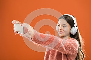 Listen for free. Mobile application for teens. Girl child listen music modern headphones and smartphone taking selfie