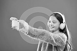 Listen for free. Mobile application for teens. Girl child listen music modern headphones and smartphone taking selfie