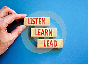 Listen learn lead symbol. Concept word Listen Learn Lead on beautiful wooden block. Businessman hand. Beautiful blue table blue