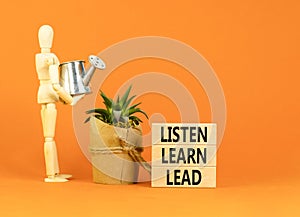 Listen learn lead symbol. Concept word Listen Learn Lead on beautiful wooden block. Businessman model. Beautiful orange table