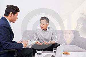 Listen to me. Asian man wrinkling forehead while looking at his therapist photo