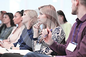 Listeners take notes in notebooks,sitting in the conference room