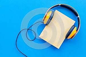 Listening audio books with headphones in library on blue background top view