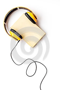 Listening audio books with headphones in library on wooden background top view