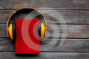 Listening audio books with headphones in library on wooden background top view space for text