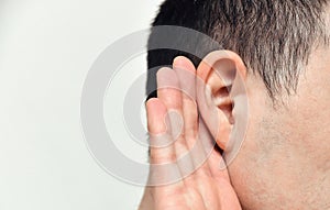 Listening man holds his hand near his ear