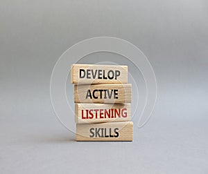 Listening skills symbol. Concept word Develop active listening skills on wooden blocks. Beautiful grey background. Business and