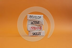 Listening skills symbol. Concept word Develop active listening skills on wooden blocks. Beautiful orange background. Business and