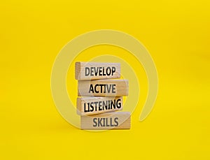 Listening skills symbol. Concept word Develop active listening skills on wooden blocks. Beautiful yellow background. Business and